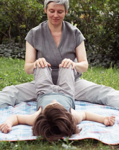 Kind liegend auf Decke mit Berührung an den Knien, hochsensibel, sanfte Berührung